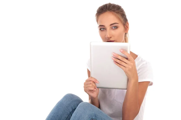 Jovem mulher casual segurando um tablet sobre o rosto — Fotografia de Stock