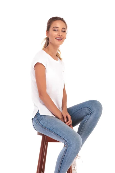 Νεαρή γυναίκα casual είναι το γέλιο ενώ κάθεται σε μια καρέκλα — Φωτογραφία Αρχείου