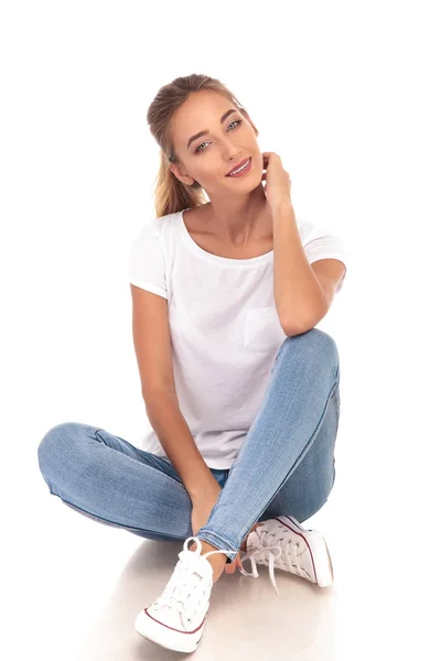 Jovem mulher em jeans, t-shirt e tênis sentado — Fotografia de Stock