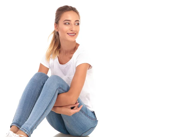 Seated young casual woman looks to side and smiles — Stock Photo, Image