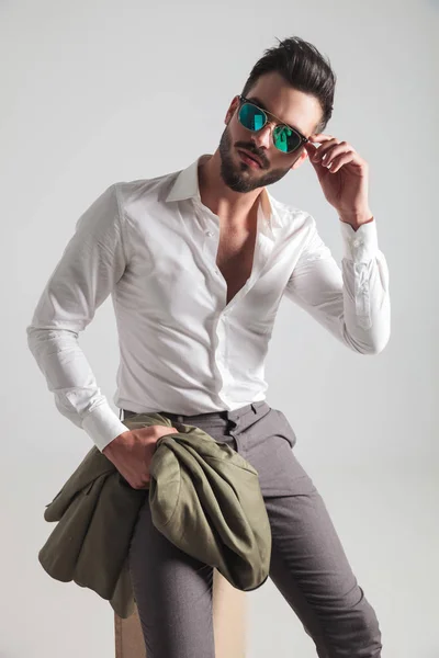 Cool fashion man sitting and putting on his sunglasses — Stock Photo, Image