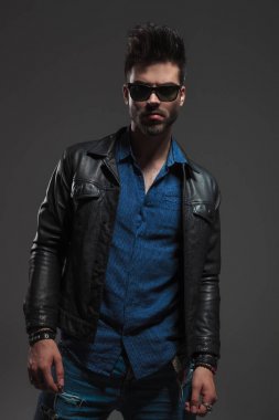 Genç hipster deri ceket ve ayakta güneş gözlüğü