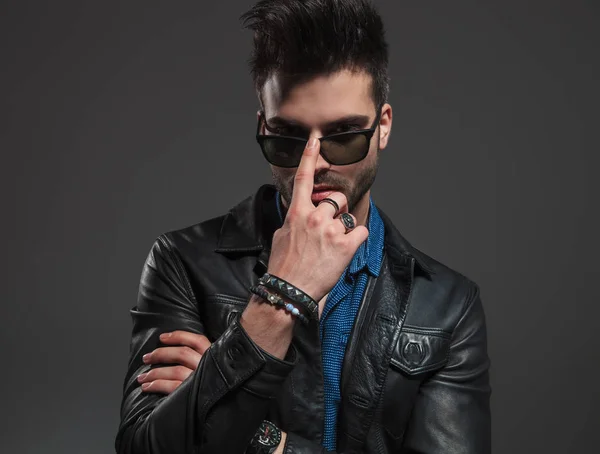 Sexy man in leather jacket pushing his sunglasses on — Stock Photo, Image