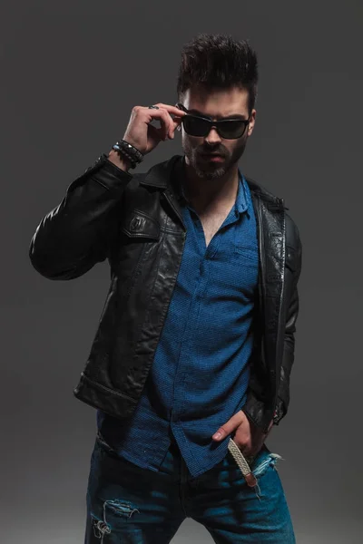 Hombre de moda dramático en chaqueta de cuero quitándose las gafas de sol — Foto de Stock