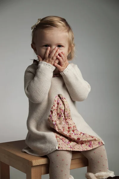 Збуджена маленька дівчинка прикриває рот долонями — стокове фото