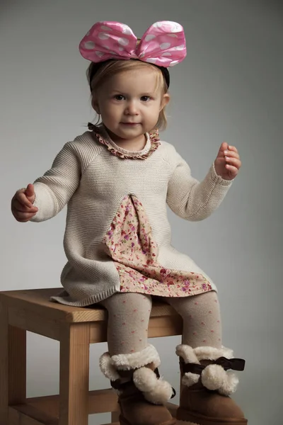 Sentada niña hermosa con una diadema de arco rosa —  Fotos de Stock