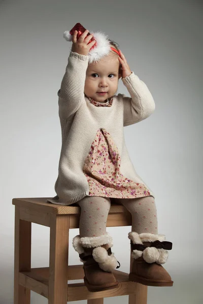 Pequena menina sorrindo está segurando seu chapéu de Natal na cabeça — Fotografia de Stock