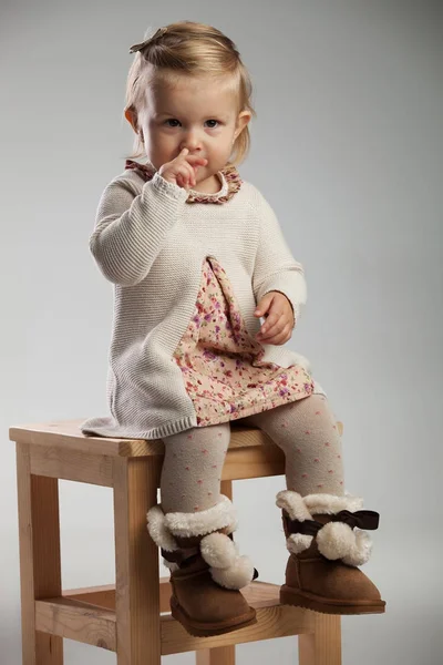 Entzückendes kleines Mädchen, das sich im Sitzen die Nase zupft — Stockfoto