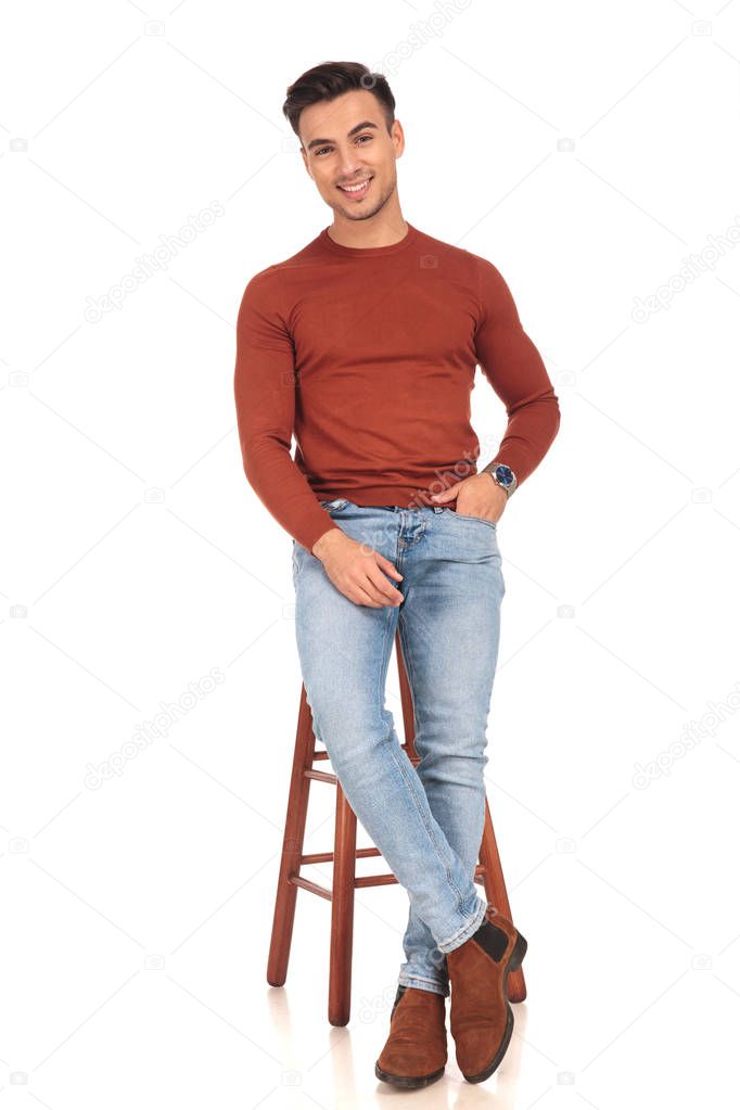casual man sitting on a stool and smiles 