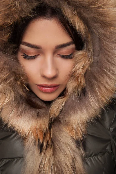 Beautiful woman wearing fur hood looks down — Stock Photo, Image