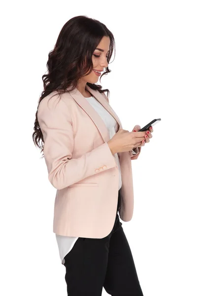 Zijaanzicht van een jonge zakelijke vrouw texting op haar — Stockfoto