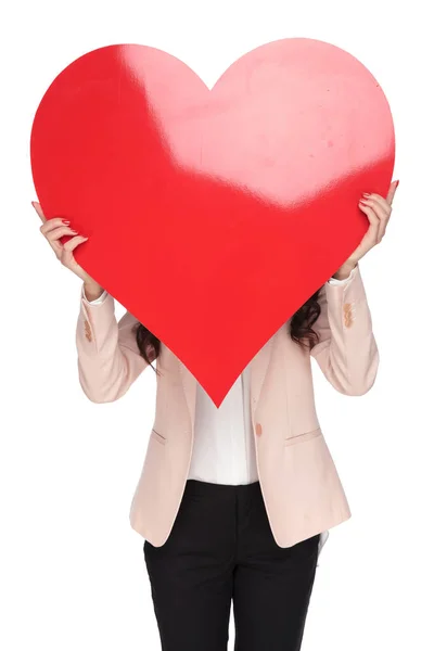 Donna che si copre il viso con una grande forma di cuore rosso — Foto Stock