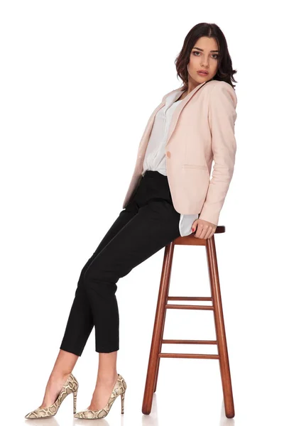 Vista laterale di una giovane donna elegante seduta su uno sgabello — Foto Stock