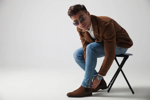 Sitzender junger Modemann, der seine Jeans repariert — Stockfoto