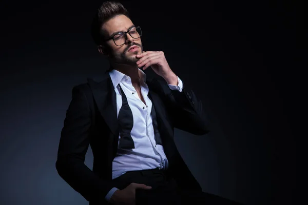 Thoughtful young elegant man in tuxedo with undone bowtie — Stock Photo, Image