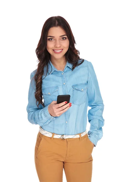 Leende kvinna anläggning telefon och SMS — Stockfoto