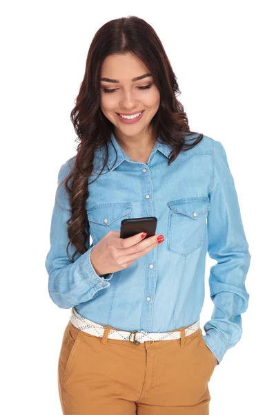 Щаслива молода жінка читає повідомлення на мобільному телефоні — стокове фото