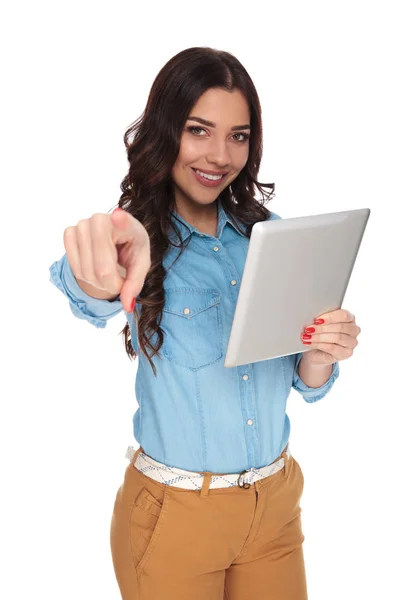 Mulher sorrindo segurando tablet aponta dedo — Fotografia de Stock