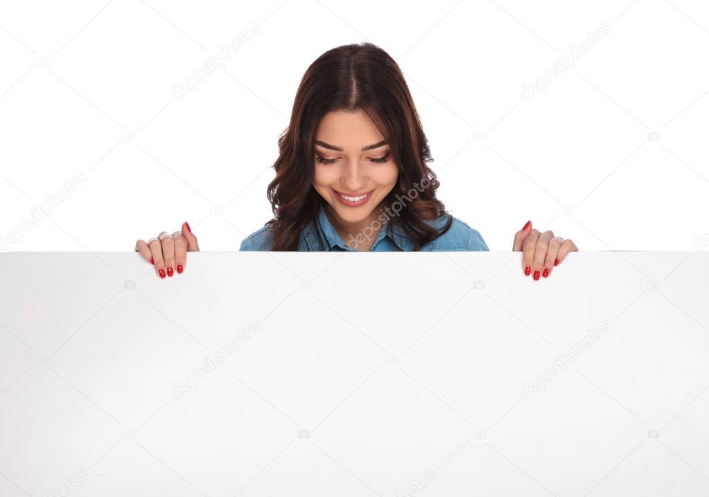 smiling casual woman standing above a big blank board 