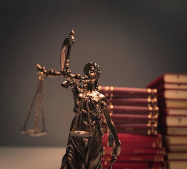 Statue de justice devant un tas de livres de droit — Photo