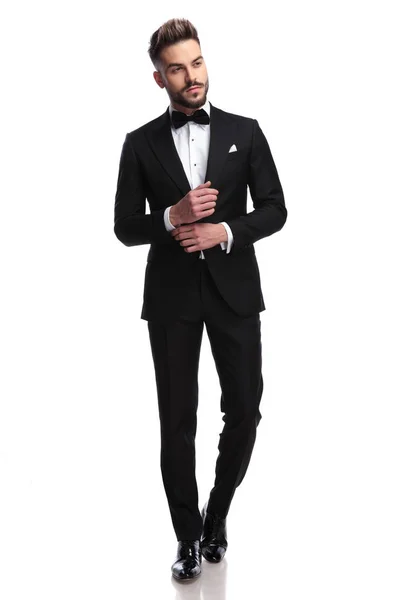 Young sexy man in tuxedo and bowtie fixing his sleeve — Stock Photo, Image