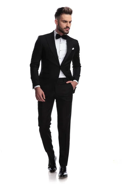 Serious handsome man in tuxedo walks and looks to side — Stock Photo, Image