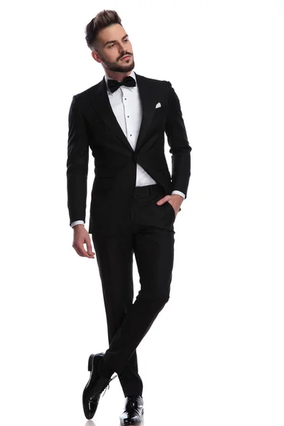 Man in tuxedo standing with hand in pocket looks away — Stock Photo, Image