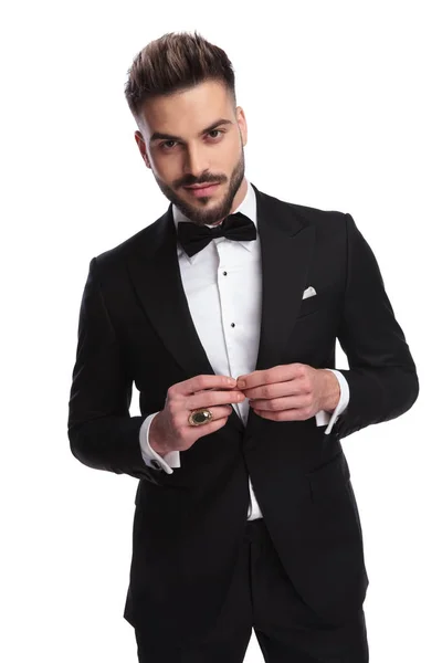 Smiling elegant man in tuxedo touching his fingers and posing — Stock Photo, Image