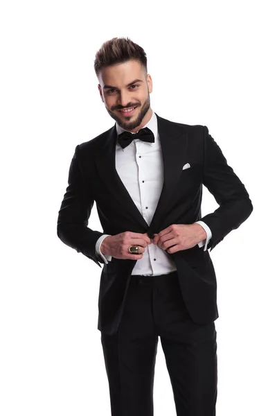 Elegante man losknopend zijn tuxedo en lacht — Stockfoto