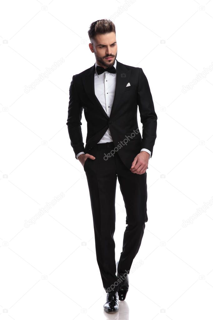 young fashion man in tuxedo walks and looks down 