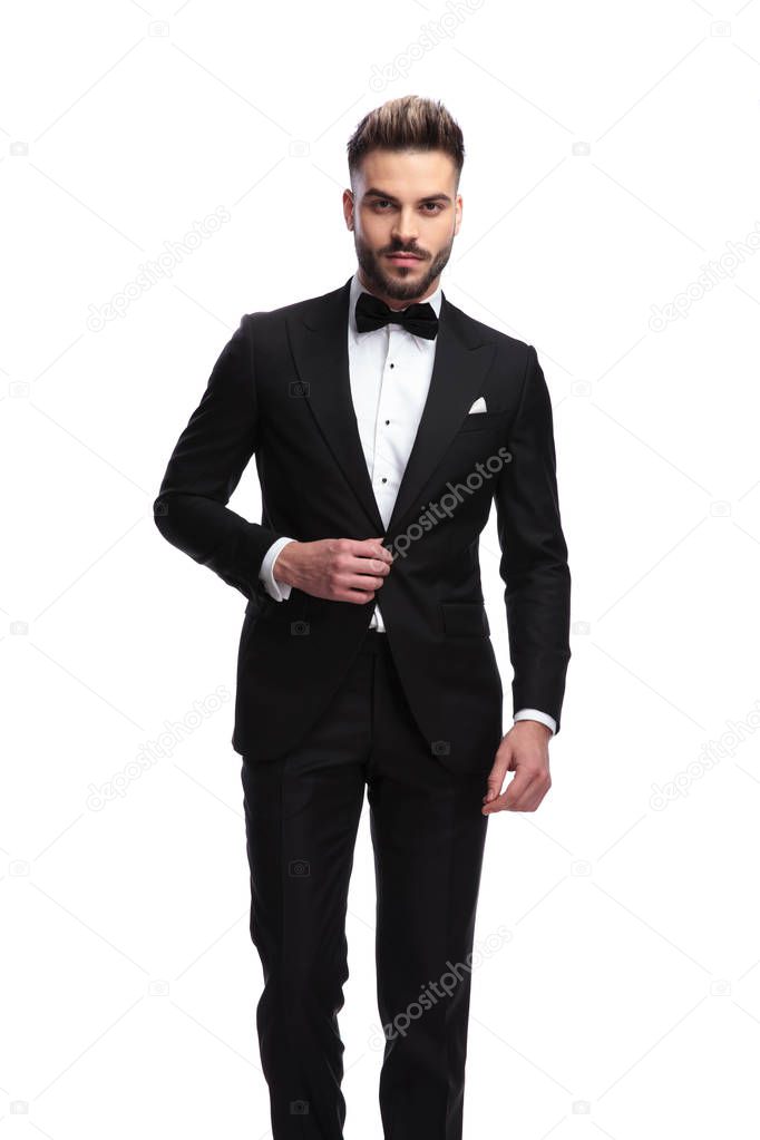portrait of a sexy man in tuxedo holding his collar 