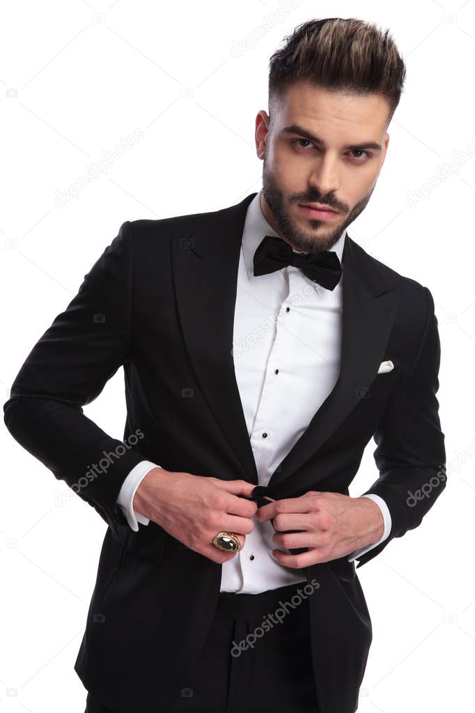 portrait of a sexy man buttoning his tuxedo