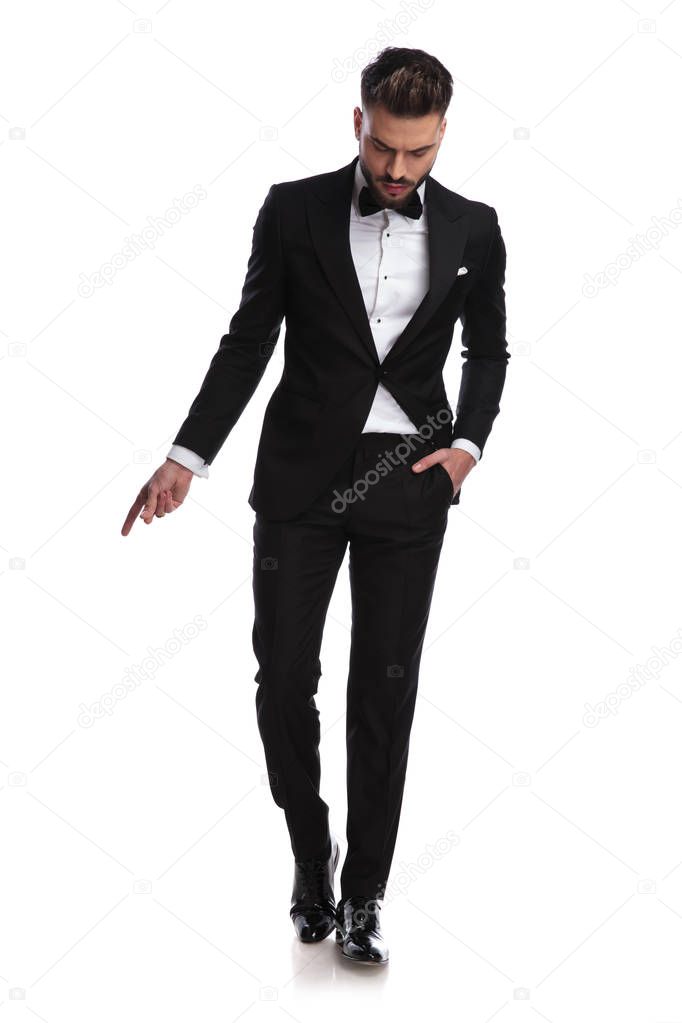 elegant man in tuxedo snapping fingers and looks down