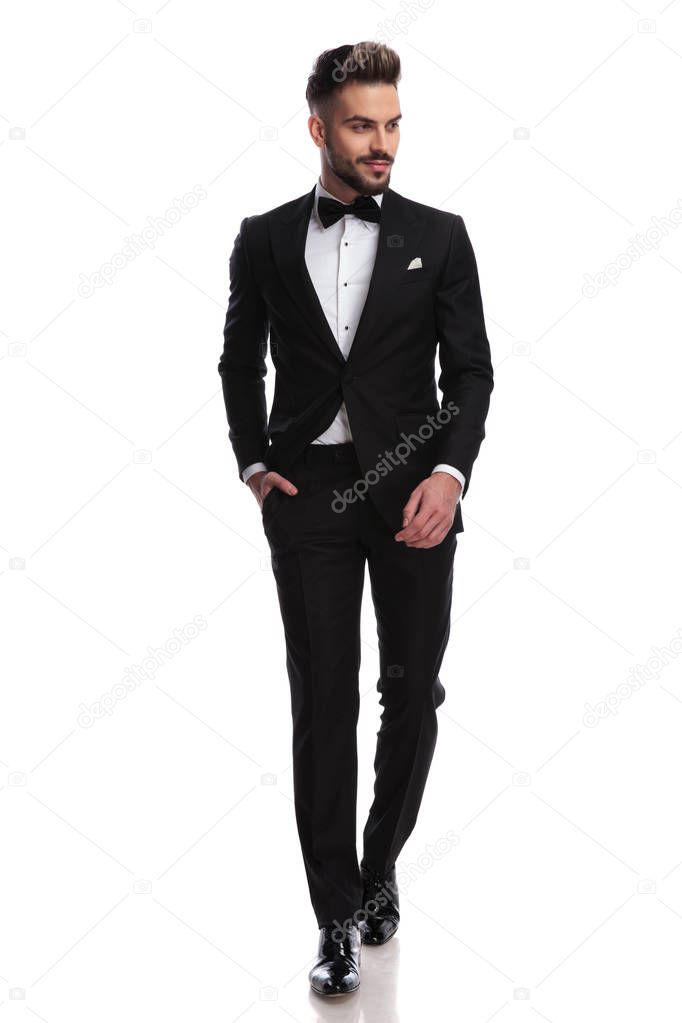 smiling young elegant man is walking and looks to side 