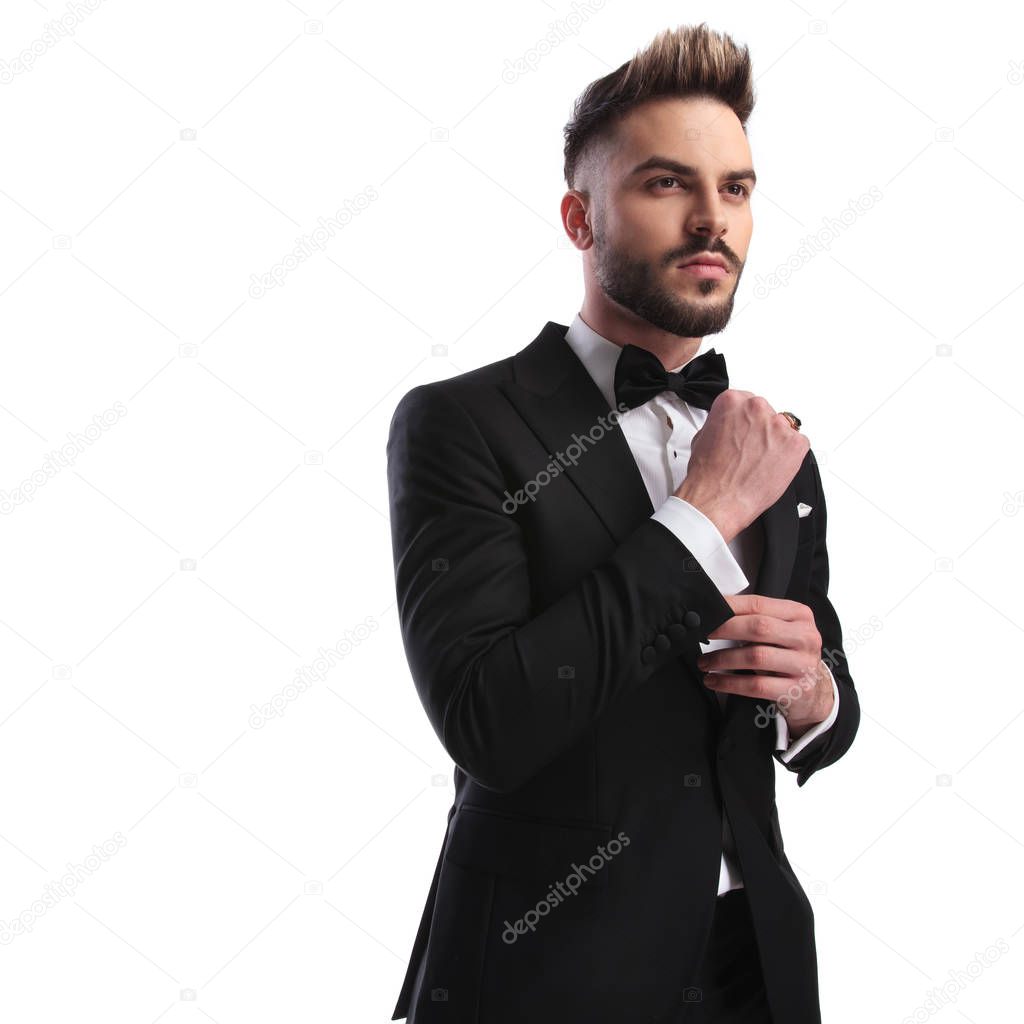 side view of fashion model in tuxedo fixing cufflinks 