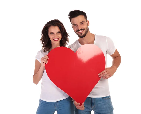 Feliz joven pareja sosteniendo gran corazón y sonriendo — Foto de Stock