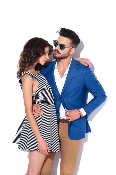 Man in sunglasses pulls coat while embracing his woman — Stock Photo, Image