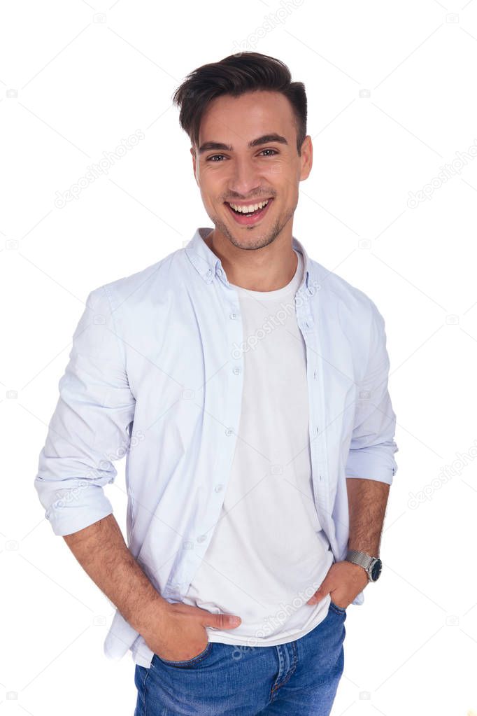 young casual man with hands in pockets is laughing 