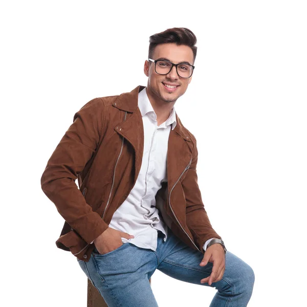 Glimlachend jongeman in leren jas en bril zit — Stockfoto