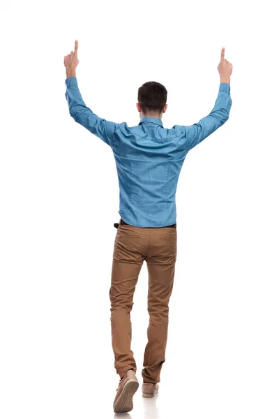 Back view of a casual man walking and pointing up — Stock Photo, Image