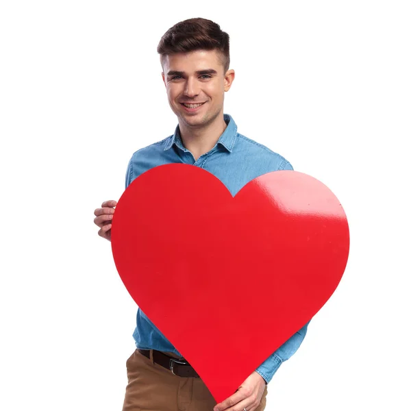 Χαμογελαστός άνθρωπος casual, κρατώντας μια μεγάλη κόκκινη καρδιά — Φωτογραφία Αρχείου