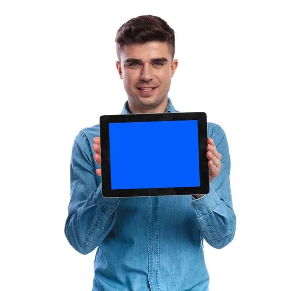 Joven hombre casual mostrando la pantalla en blanco de una tableta — Foto de Stock