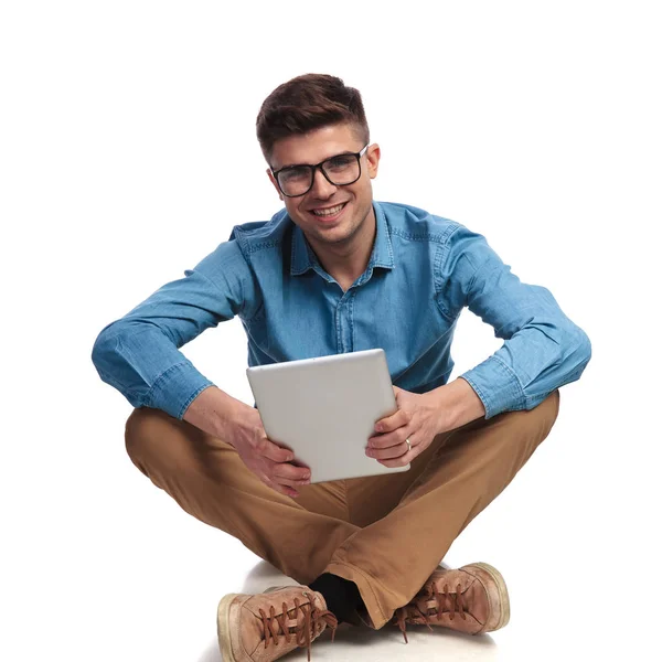 Sittande ung casual man håller tablett — Stockfoto