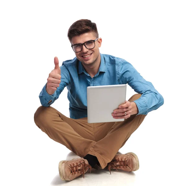 Aluno sentado lendo boas notícias no tablet e faz ok — Fotografia de Stock