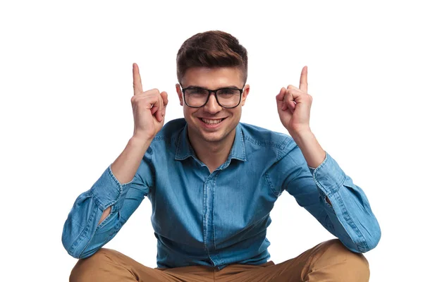 Genç gülümseyen adam başını parmakları işaret oturmuş — Stok fotoğraf