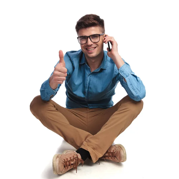 Zittende casual man praten over de telefoon maakt ok teken — Stockfoto