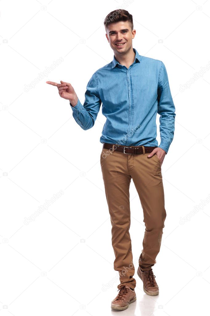 happy young casual man pointing finger to side 