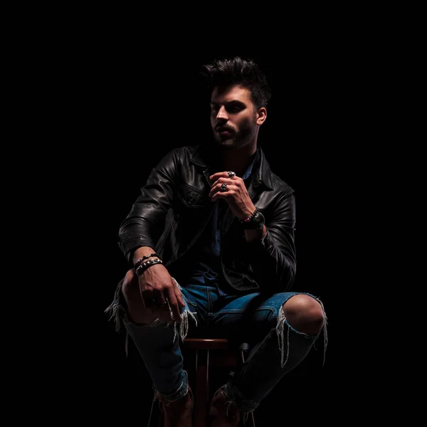 Impactado hombre de moda en chaqueta de cuero sentado se ve a un lado — Foto de Stock