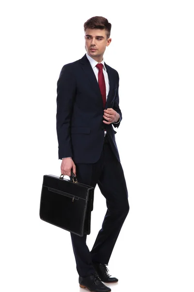 Uomo d'affari guarda a lato mentre tiene la sua valigetta — Foto Stock