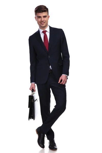 Расслабленный бизнесмен со скрещенными ногами и портфелем в руке — стоковое фото